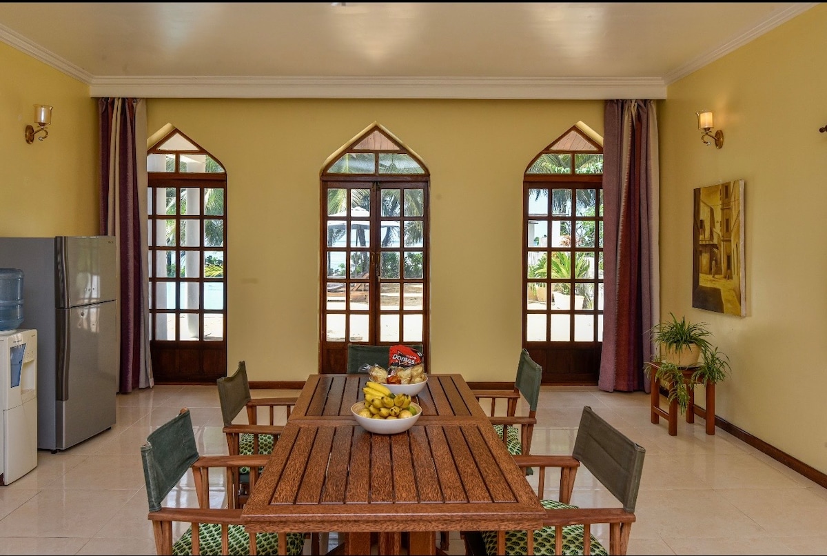 Dining room with arched windows and view to pool and palms